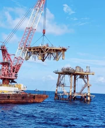 Crane lifting away part of an offshore structure being decommissioned.