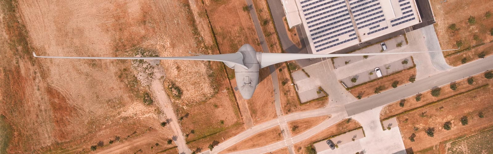 Aerial view looking down on top of a wind turbine and a building  rooftop covered in solar panels