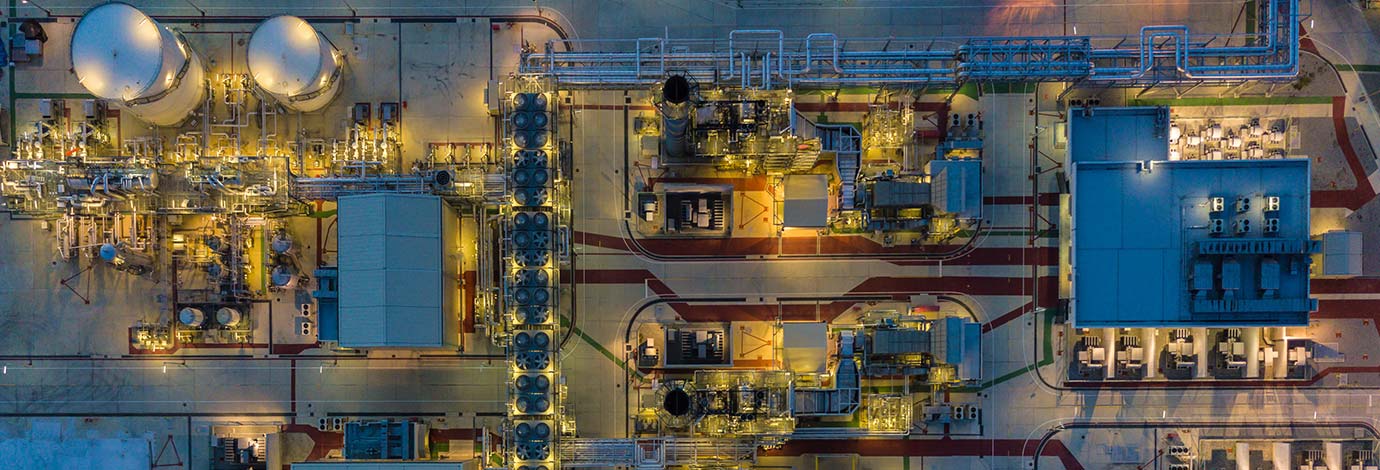 Aerial top view of a chemical and oil plant, illuminated by yellow lights.