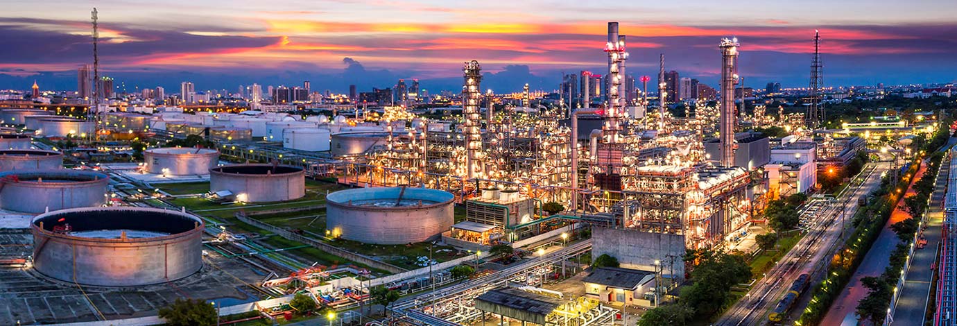 Aerial view of oil gas chemical refinery plant with sun setting and pink sky.